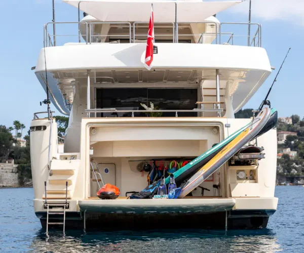 Luxurious yacht exterior of the Ferretti Custom Line Navetta 26 'La Pausa', with water sports equipment, on clear sea water.