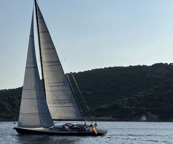 Elegant sailing yacht with large sails on tranquil sea.