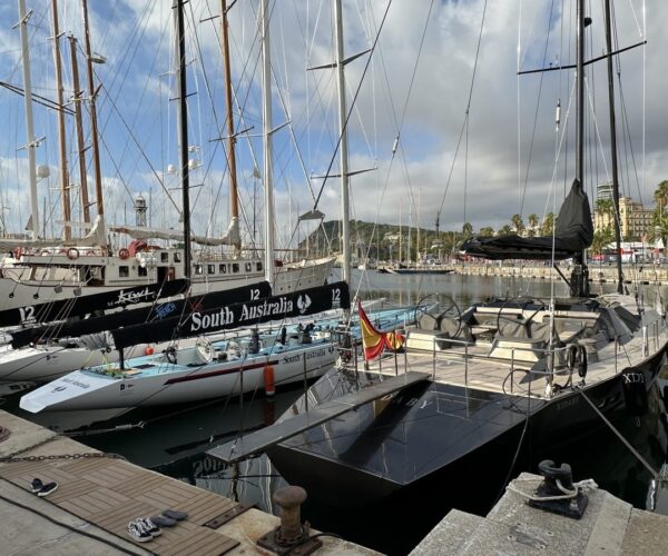 Luxury yachts docked at marina with masts and sails.