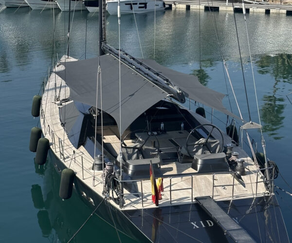 Elegant black sailing yacht docked in harbour with modern design.