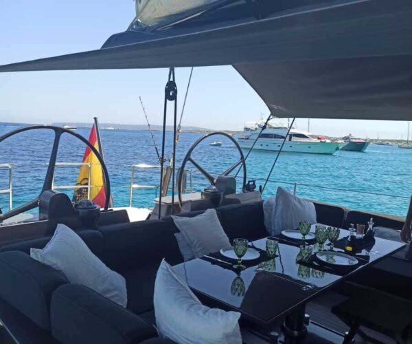 Outdoor dining space on a yacht with sea and other boats in the background.