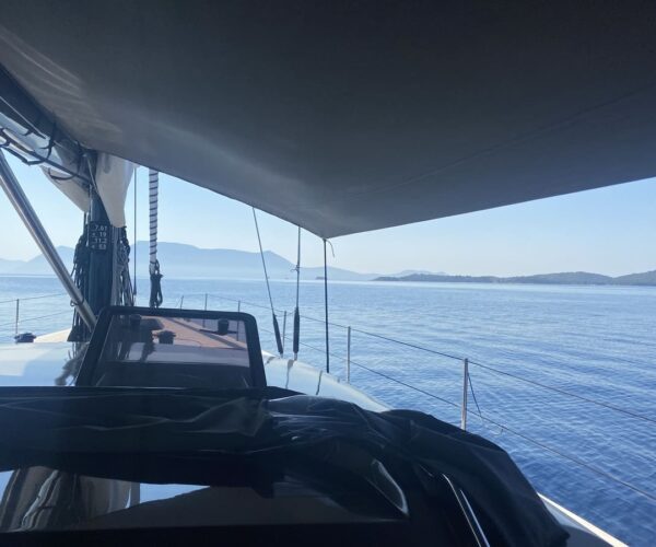 View of yacht deck and calm sea with distant islands.