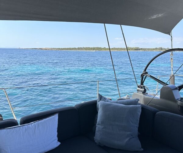 Seating area on a luxury yacht with ocean and distant island view.