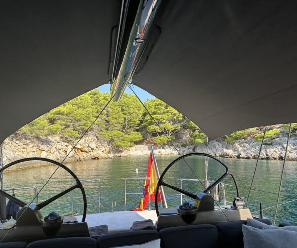 Yacht deck with shaded canopy, view of water and surrounding landscape.
