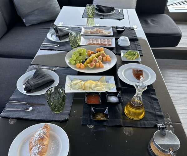 Elegant outdoor dining on a yacht with fresh food and drinks.